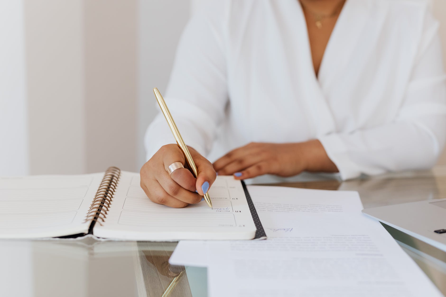 person in white top writing on notebook